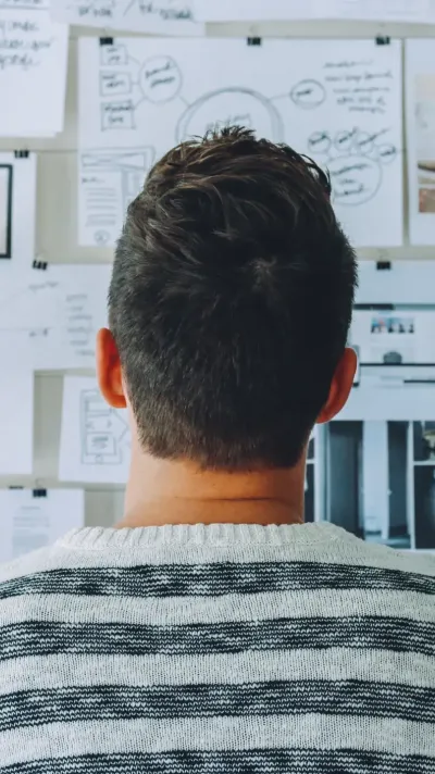 Een ondernemer die naar papieren aan de muur kijkt Een ondernemer die naar papieren aan de muur kijkt