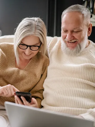 Ouder koppel kijkt op telefoon en laptop