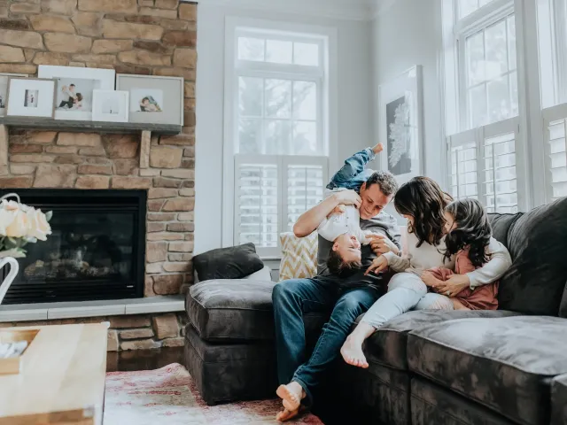 Des parents et leurs enfants jouent ensemble sur le canapé de leur salon.