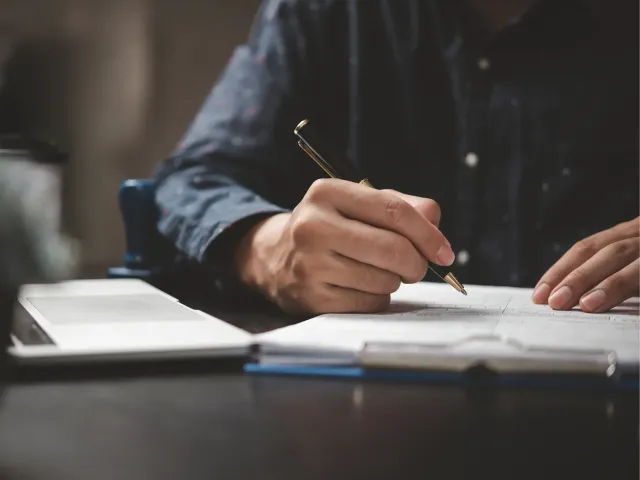 Man zit aan bureau en schrijft op papier