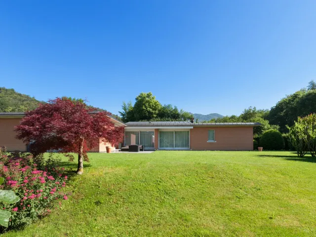 Une maison avec son jardin au soleil.