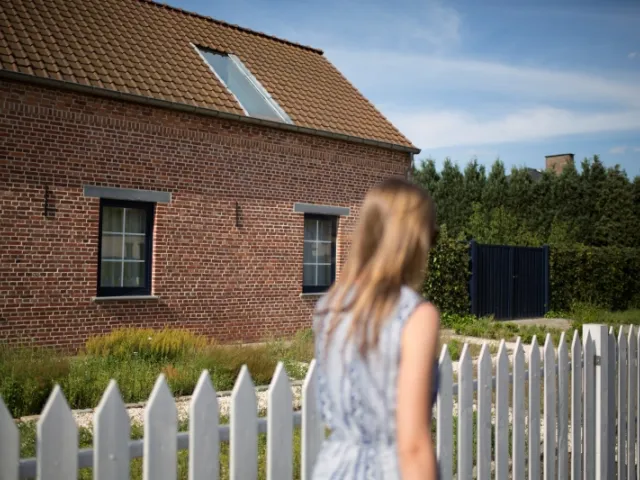 Une jeune femme devant une maison située en Flandre en Belgique