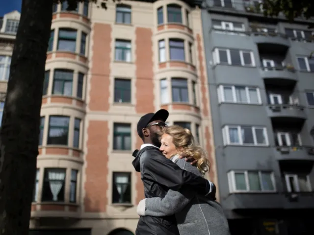 Un couple s'enlace devant un immeuble d'appartements à Bruxelles.