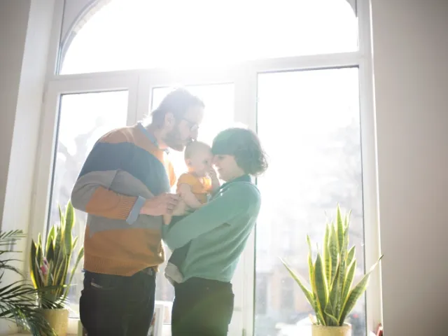 Un couple embrasse leur enfant dans leur habitation en Belgique.