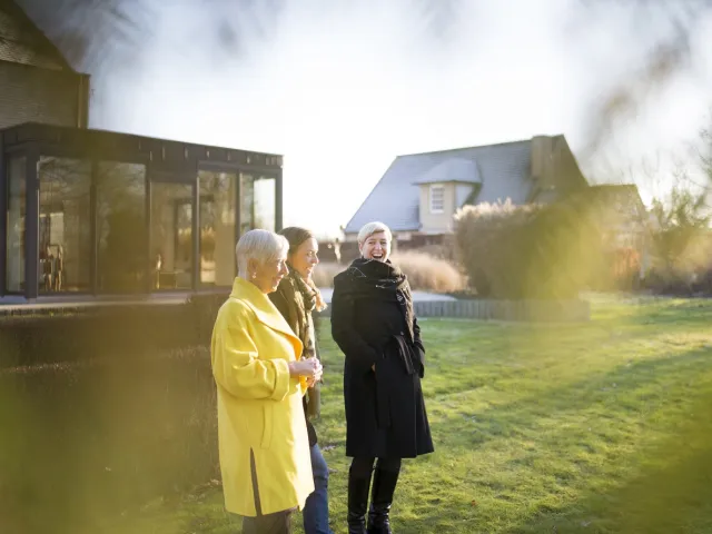 Trois générations de femmes discutent dans leur jardin d'une donation d'une maison en Belgique.