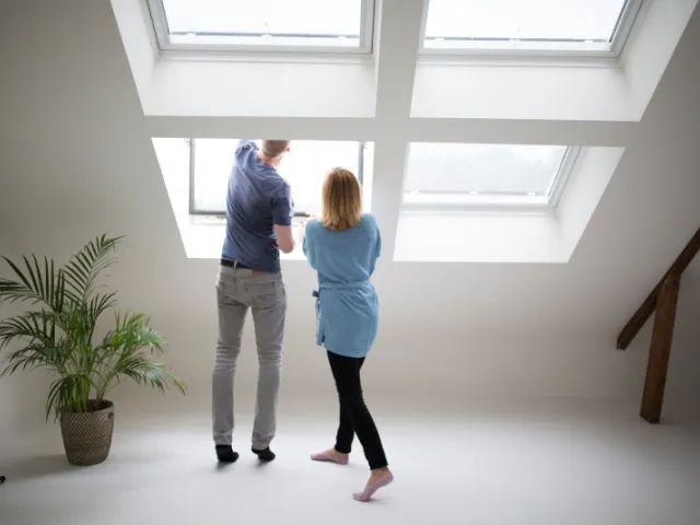 Un couple analyse l'isolation des fenêtres de leur maison pour connaitre la performance énergétique (PEB) de leur habitation.