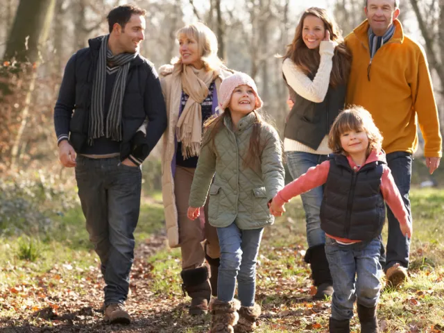 Une famille (grands-parents, parents et enfants) se promène dans les bois en Belgique, sereins car leur planification de succession a été réglée par leur notaire.