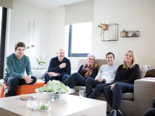 Des parents et leurs trois enfants assis sur leur canapé discutent de donations.